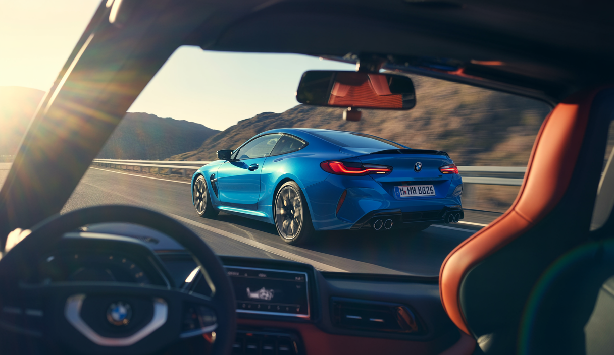 La BMW M8 supercar de couleur bleu métallisé, vue de profil sur une route de montagne, alliant élégance et performance extrême.