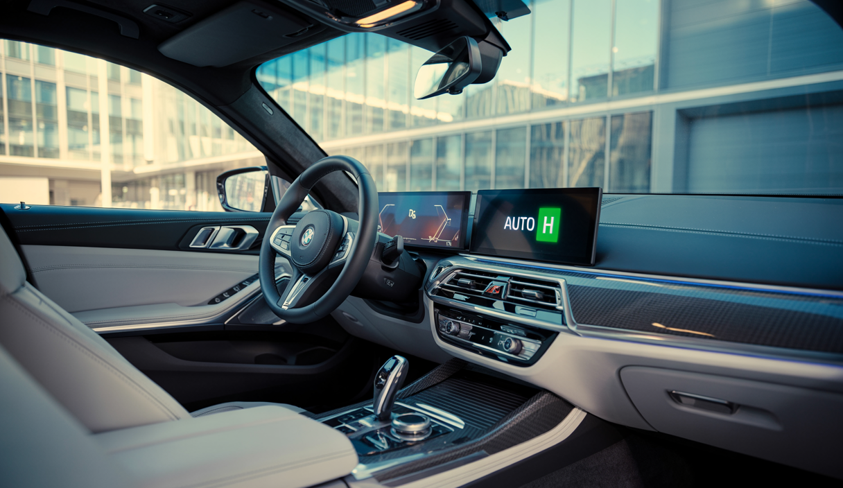 Vue rapprochée d'une BMW équipée de la fonction Auto Hold, montrant un intérieur luxueux avec le tableau de bord et le bouton Auto Hold activé sur la console centrale.